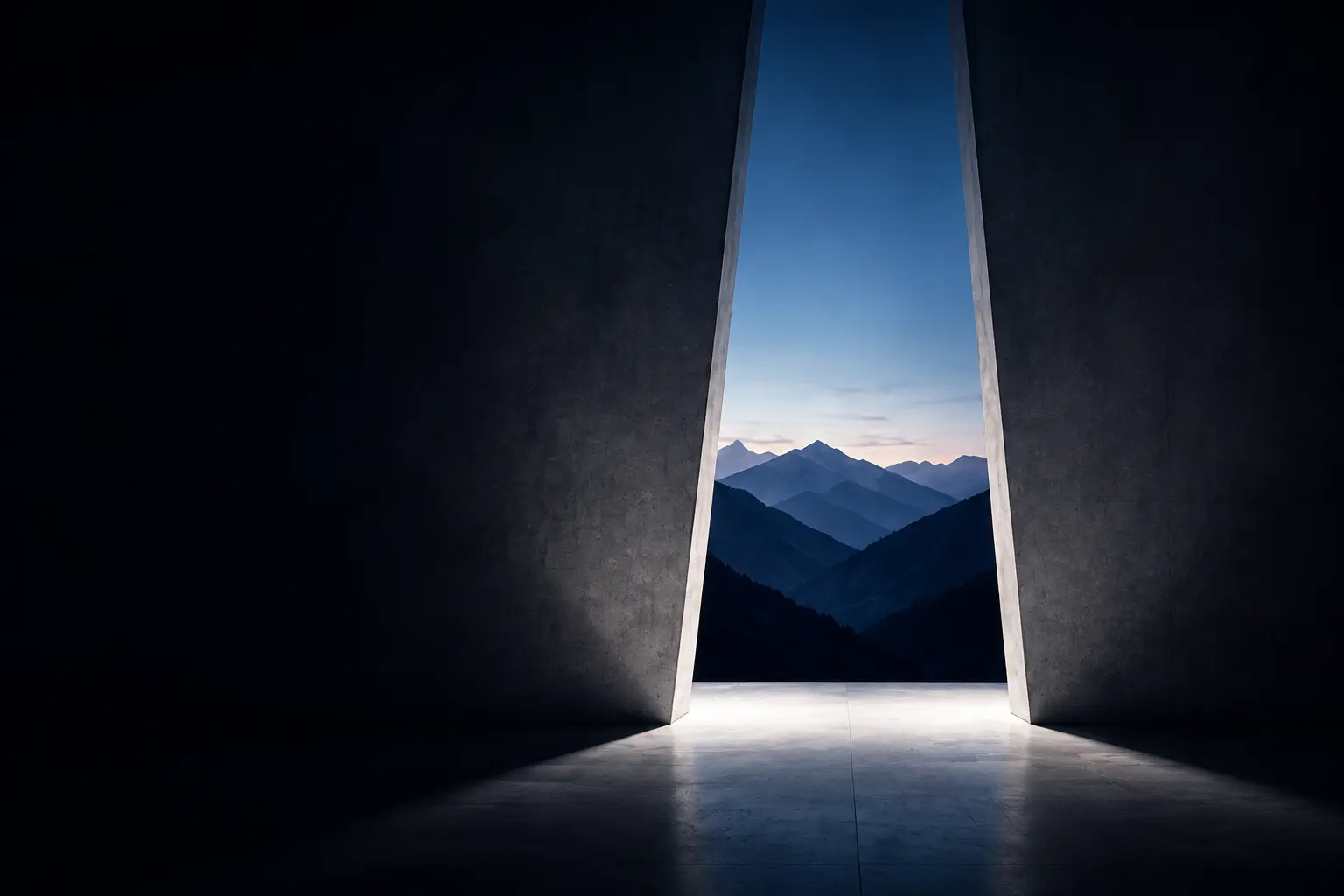 Wide angled architectural opening in concrete walls looking out toward layered distant mountains at dusk